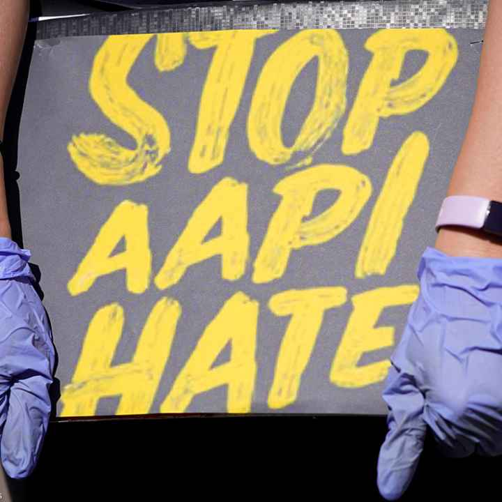 Woman holds a sign stating “Stop AAPI Hate.”