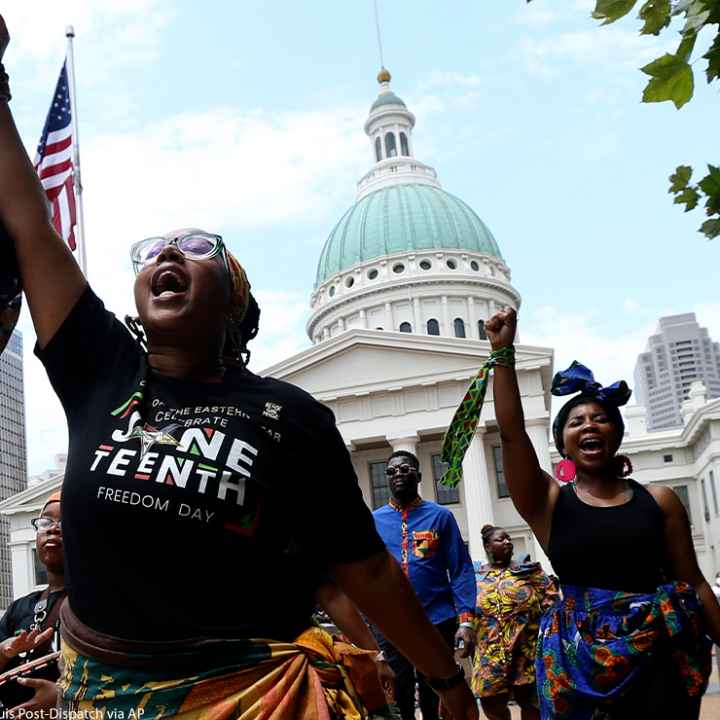 Marchers commemorating Juneteenth walking with fists raised in front of the Old Courthouse in St. Louis.